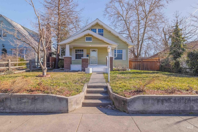 bungalow-style house with fence, a front lawn, and brick siding