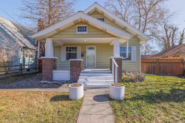 view of front of home with fence, a porch, and a front yard