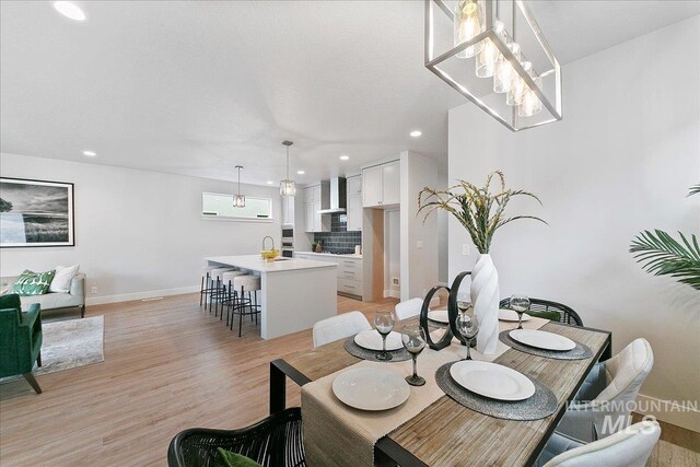 dining room featuring sink, a notable chandelier, and light wood-type flooring