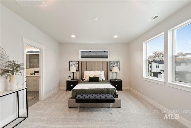 carpeted bedroom with ensuite bath and multiple windows