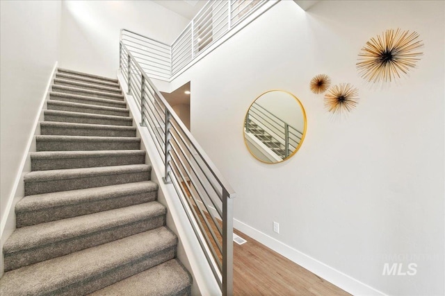 stairs with hardwood / wood-style floors and a towering ceiling