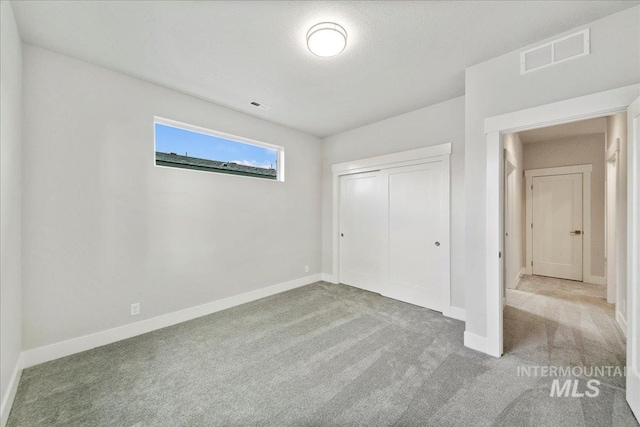 unfurnished bedroom featuring light carpet and a closet