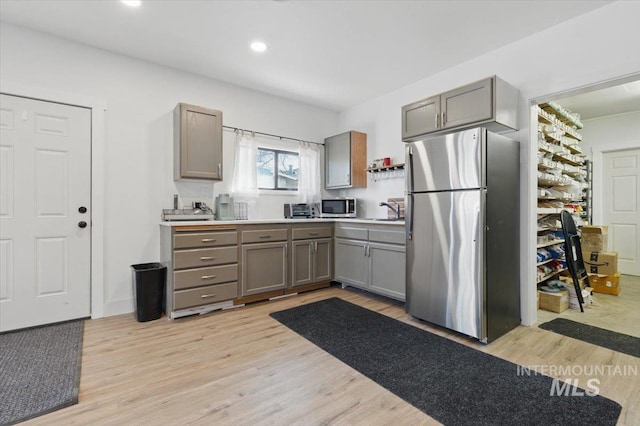 4320 N Locust Grv, Meridian, ID 83642 - kitchen with light wood-type flooring, light countertops, gray cabinets, a sink, and stainless steel appliances