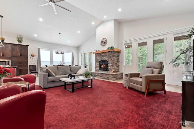 carpeted living room featuring ceiling fan, a stone fireplace, and high vaulted ceiling