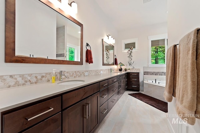 bathroom featuring vanity, tile patterned floors, and tiled bath