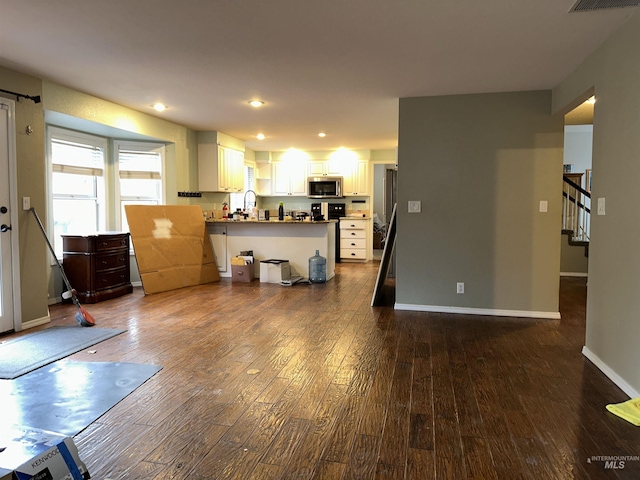 interior space with white cabinets, dark hardwood / wood-style floors, kitchen peninsula, and sink