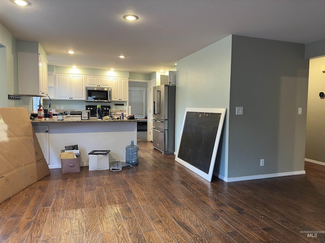 kitchen featuring white cabinets, stainless steel appliances, kitchen peninsula, and dark wood-type flooring