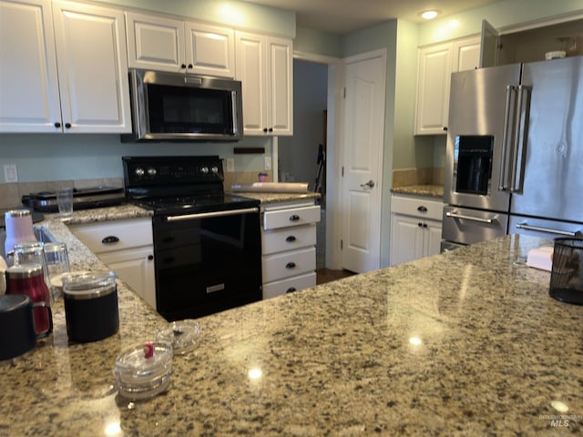 kitchen with appliances with stainless steel finishes, white cabinetry, and light stone counters