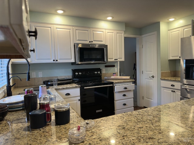 kitchen with light stone countertops, stainless steel appliances, white cabinetry, and sink