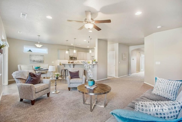 living area with light carpet, ceiling fan, arched walkways, baseboards, and recessed lighting