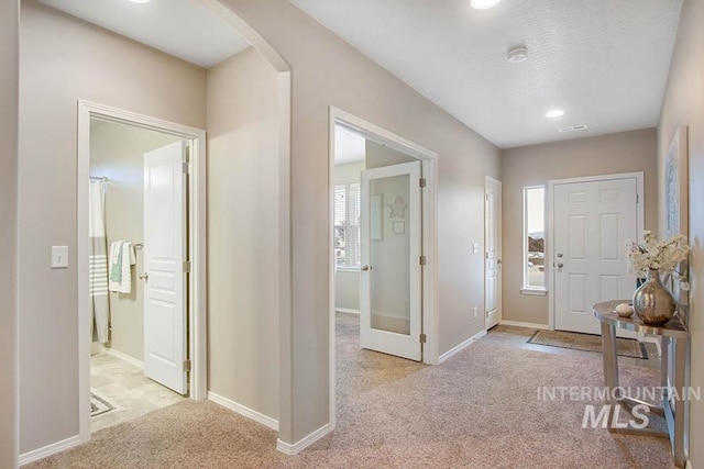 carpeted entryway with arched walkways, baseboards, and recessed lighting