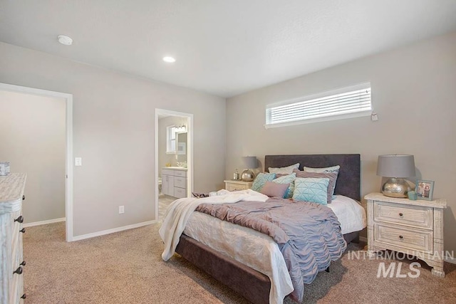 bedroom with light colored carpet, baseboards, and ensuite bath