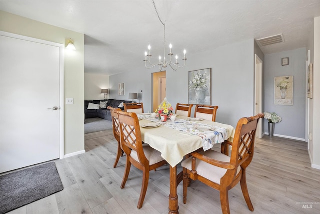dining space with baseboards, visible vents, light wood-type flooring, and a chandelier