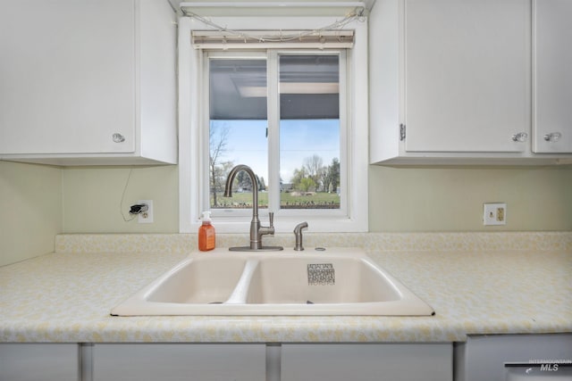 kitchen featuring a sink, light countertops, and white cabinetry