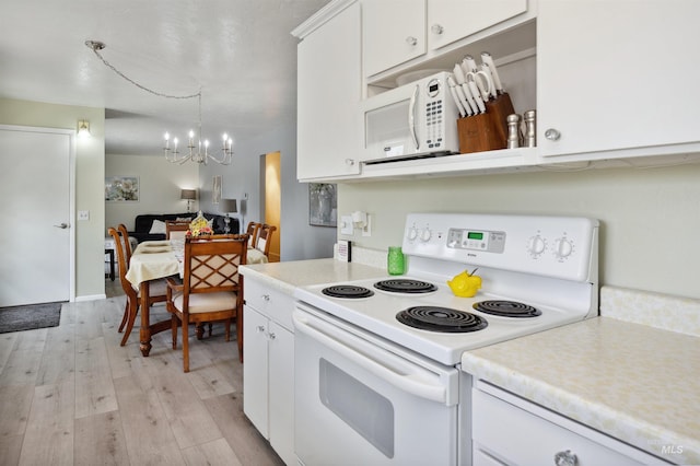 kitchen with white appliances, a notable chandelier, light wood finished floors, and light countertops