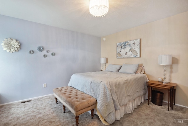 carpeted bedroom with baseboards, an inviting chandelier, and visible vents