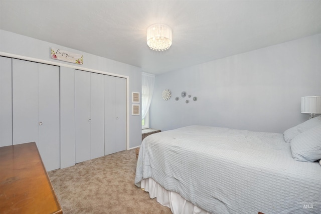 bedroom featuring light carpet, a closet, and a notable chandelier