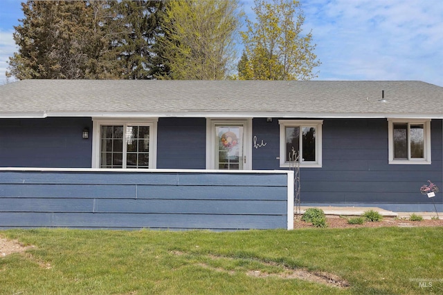ranch-style house featuring a shingled roof and a front yard