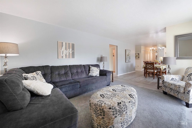 living room with an inviting chandelier, baseboards, and light colored carpet