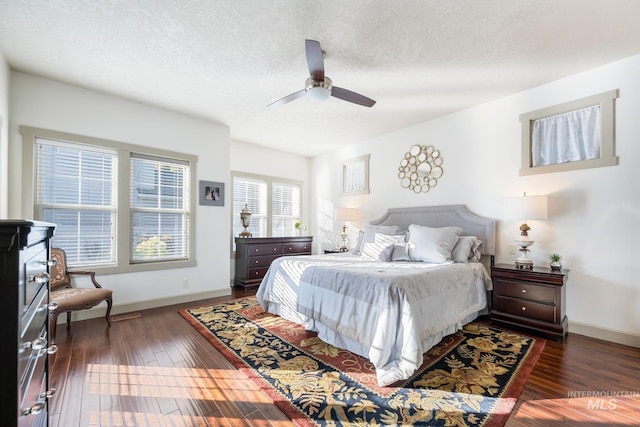 bedroom with dark wood-type flooring, ceiling fan, and a textured ceiling