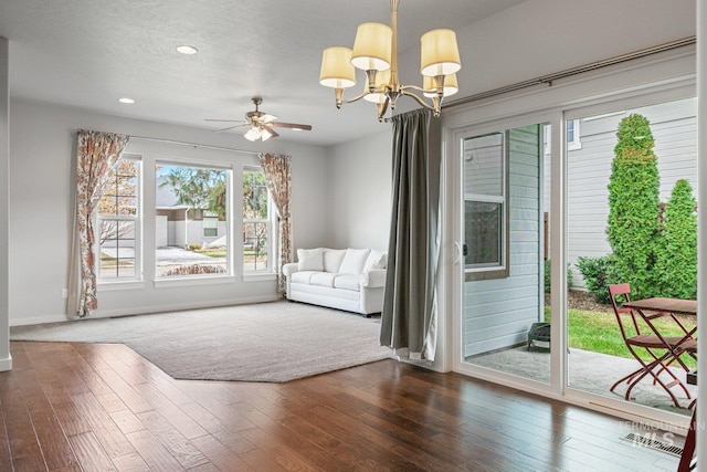 doorway to outside with ceiling fan with notable chandelier, a textured ceiling, and wood-type flooring