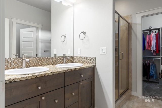 bathroom with vanity, walk in shower, and tasteful backsplash