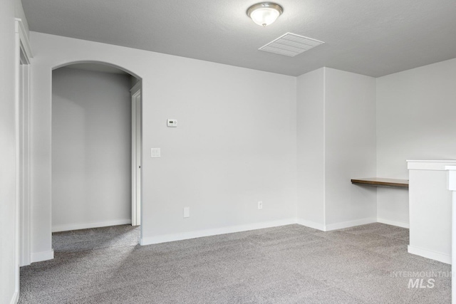 carpeted empty room featuring a textured ceiling