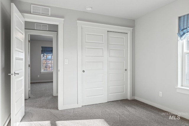 unfurnished bedroom with light colored carpet and a closet