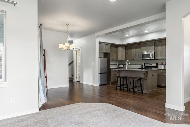 kitchen with a center island, a kitchen bar, appliances with stainless steel finishes, dark brown cabinetry, and pendant lighting