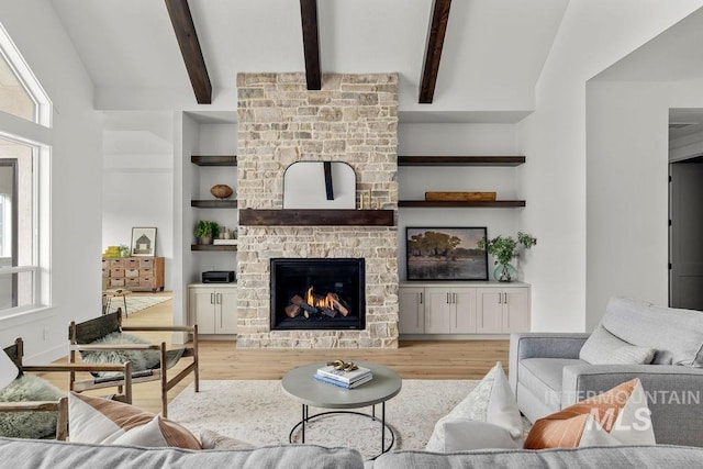 living room featuring lofted ceiling with beams, a fireplace, wood-type flooring, and built in features