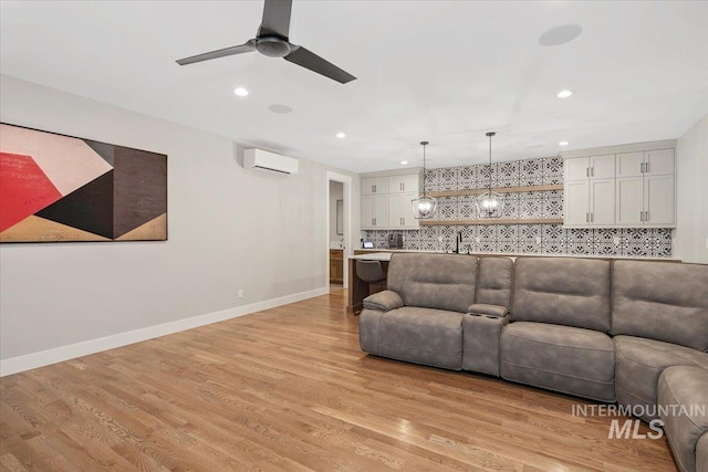 living room with baseboards, recessed lighting, light wood-type flooring, and a wall mounted air conditioner