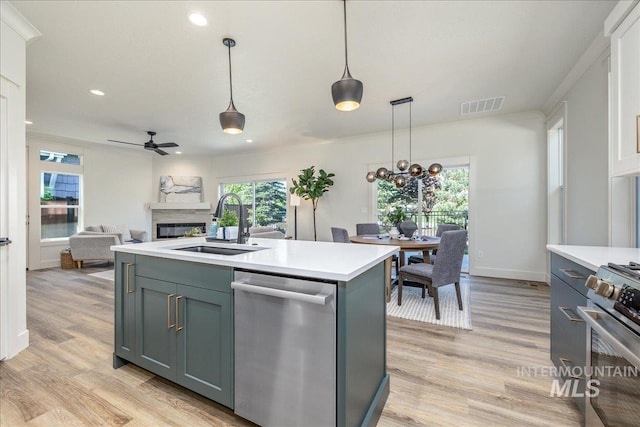 375 N Sauer River Ln, Eagle, ID 83616 - kitchen featuring stainless steel appliances, a sink, a glass covered fireplace, light countertops, and ceiling fan