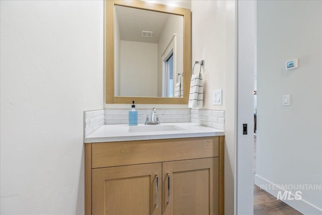 375 N Sauer River Ln, Eagle, ID 83616 - bathroom featuring vanity, decorative backsplash, baseboards, and wood finished floors