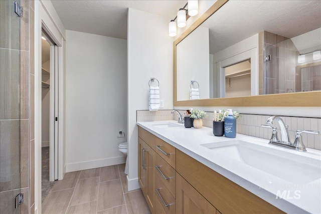 375 N Sauer River Ln, Eagle, ID 83616 - bathroom featuring a spacious closet, toilet, double vanity, and tasteful backsplash