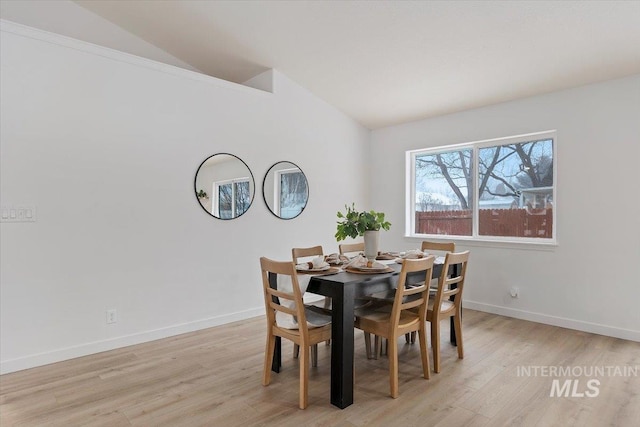 dining area featuring lofted ceiling, light wood finished floors, and baseboards