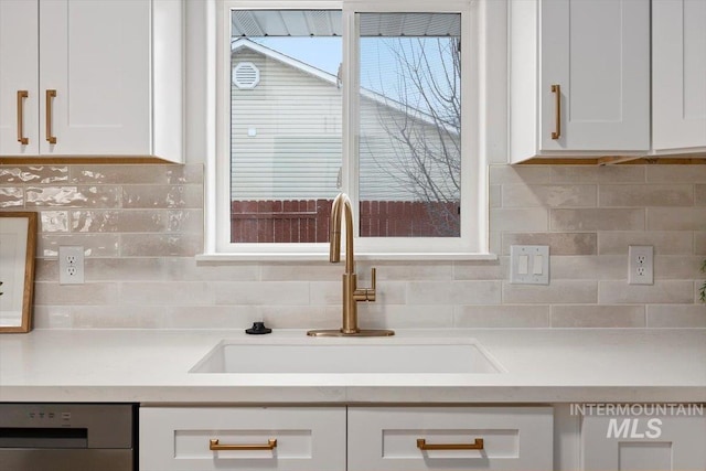 kitchen with light countertops, a sink, dishwashing machine, and white cabinetry