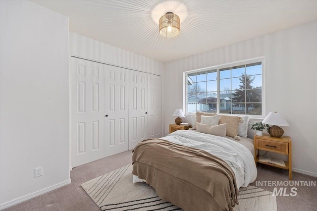 carpeted bedroom featuring a closet and baseboards