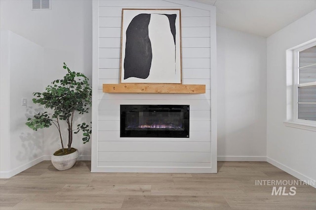 interior details featuring a large fireplace, baseboards, visible vents, and wood finished floors