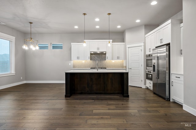 kitchen with pendant lighting, dark wood-type flooring, white cabinets, stainless steel fridge, and an island with sink