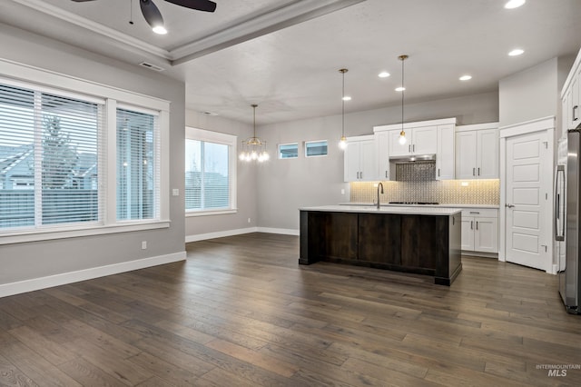 kitchen with white cabinetry, backsplash, a kitchen island with sink, and decorative light fixtures