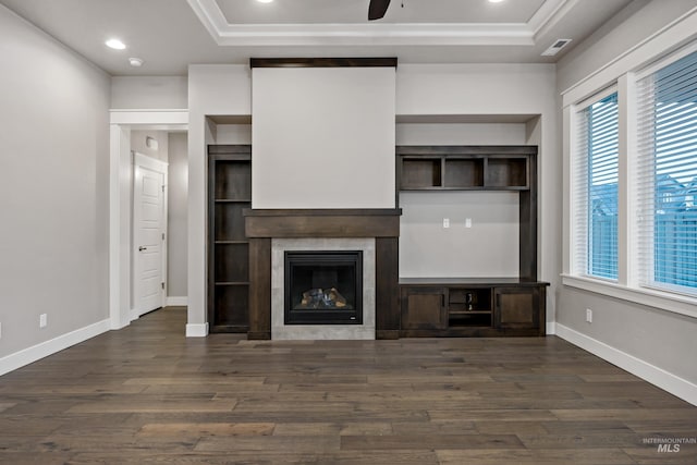 unfurnished living room with a tray ceiling, a wealth of natural light, dark wood-type flooring, and ceiling fan