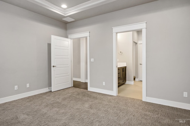 unfurnished bedroom featuring light carpet, connected bathroom, and a tray ceiling