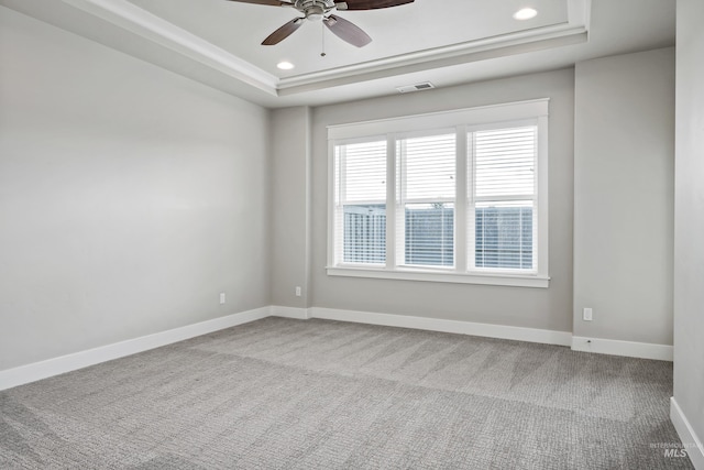 empty room featuring a tray ceiling, ceiling fan, and carpet flooring