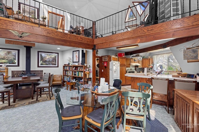 tiled dining room featuring a towering ceiling and a wood stove