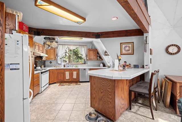 kitchen featuring light tile patterned flooring, a breakfast bar, tile countertops, kitchen peninsula, and white appliances