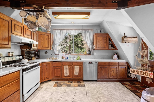 kitchen featuring white gas range, stainless steel dishwasher, tile counters, and light tile patterned floors