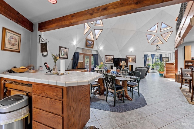 kitchen featuring beamed ceiling, a healthy amount of sunlight, tile counters, and high vaulted ceiling