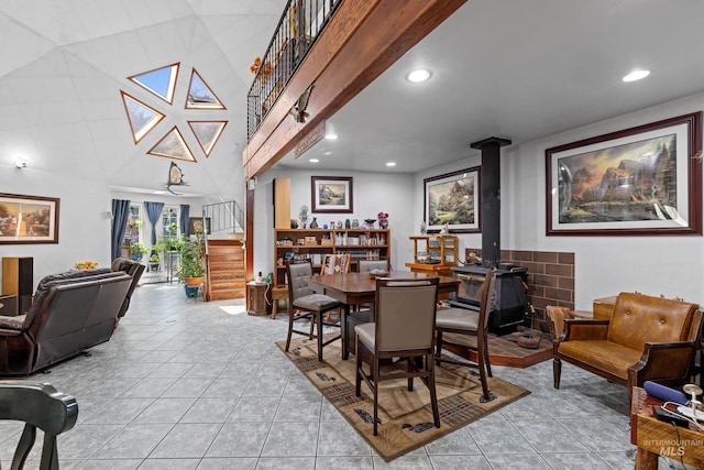 dining room with a high ceiling, a wood stove, and light tile patterned floors