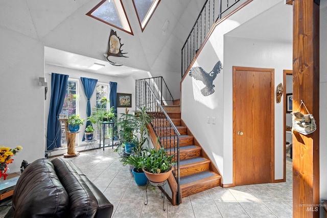 tiled entryway featuring high vaulted ceiling and a skylight