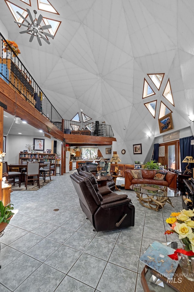 living room with a towering ceiling, a skylight, and tile patterned flooring